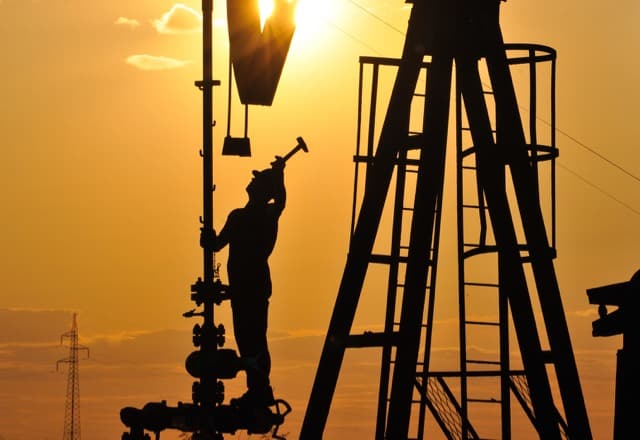 amazing facts about the oil industry illustration - Oilfield worker on a rig at sunset